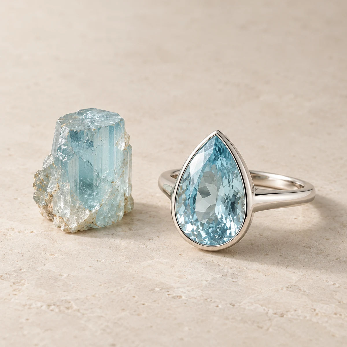 AI-created Aquamarine design inspiration: a rough specimen beside a Pear bezel ring in one scene